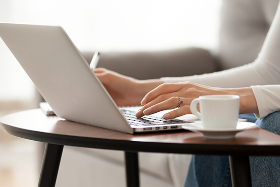 Close,up,woman,using,laptop,,sitting,on,sofa,,female,hands