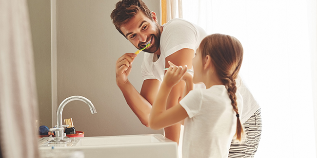 father and daughter brush their teeth together