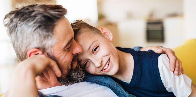 father hugging son on couch