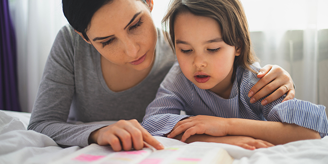Mother,and,her,daughter,reading,from,bible,and,praying,in