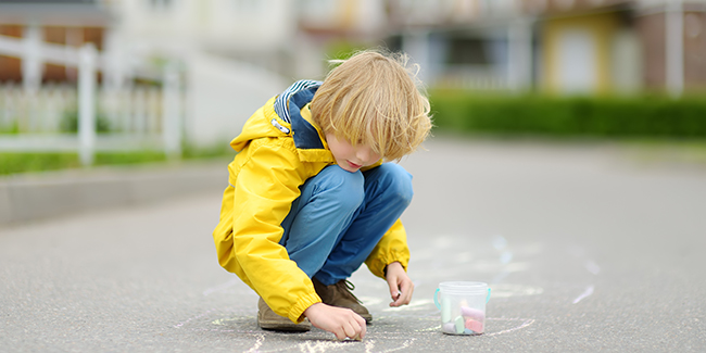 Boy drawing with chalk on the sidewalk